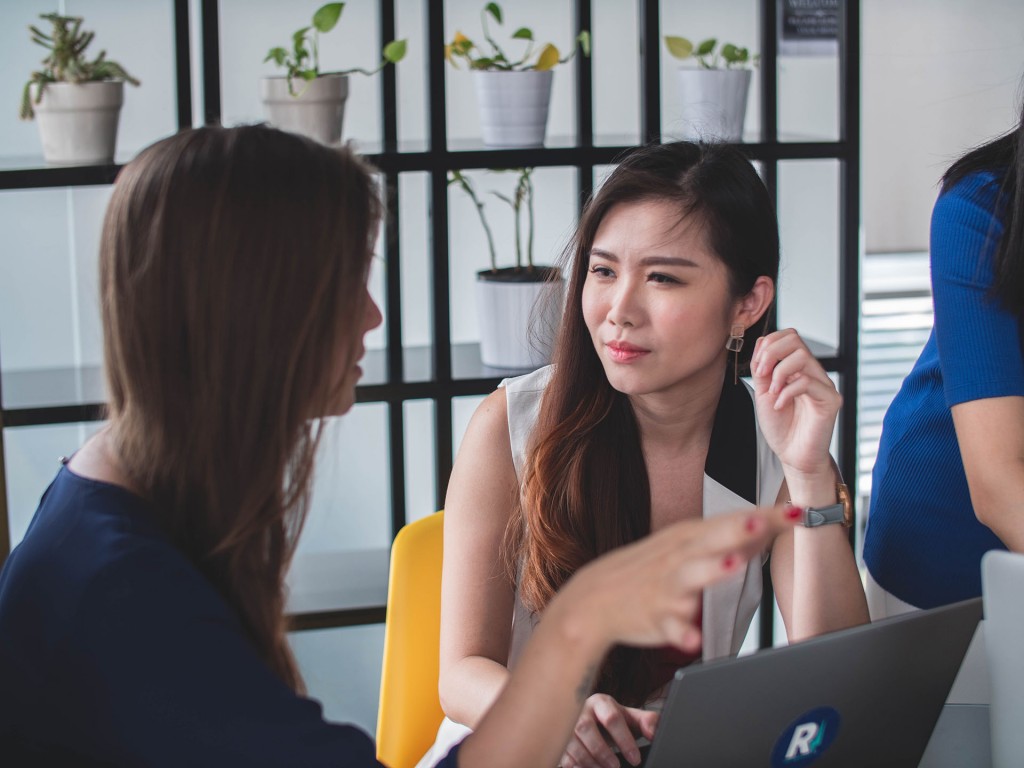 Two women talking, one looking confused and gaslighted