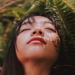 woman in sun next to plant