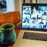 coffee mug on desk next to laptop that has a zoom call