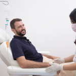 man sitting in medical chair with IV and nurse tending to him