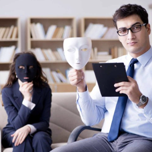 A woman covering her face with a mask, and a man holding a mask up