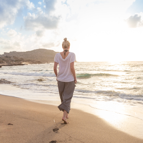 Woman walking on the beach, contemplating