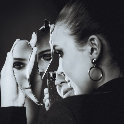woman looking at shattered mirror